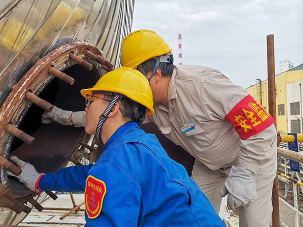 10月17日下午，在52工段除氧器人孔外，屈煒正在給董宇斌講述內部構造及工作原理。.jpg